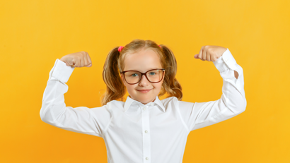 Schoolgirl in uniform flexing muscles to demonstrate strength