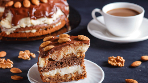 Close-up of cake slice with coffee, nuts and and more cake in the background