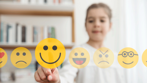 Young girl choosing selecting a happy icon from a range of emojis.