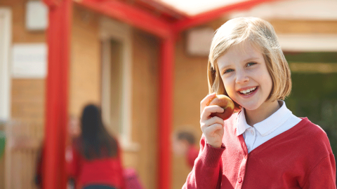 Blonde primary school girl eating an apple