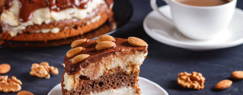Close-up of cake slice with coffee, nuts and and more cake in the background