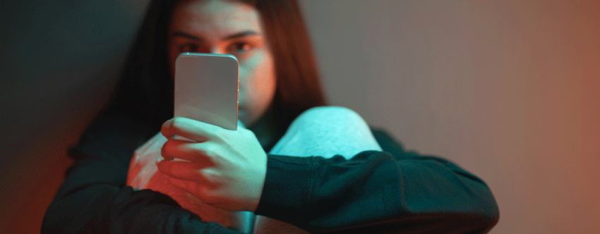 Teenage girl sat on floor, absorbed in mobile phone content