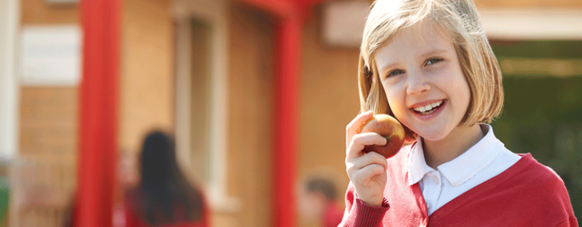 Blonde primary school girl eating an apple